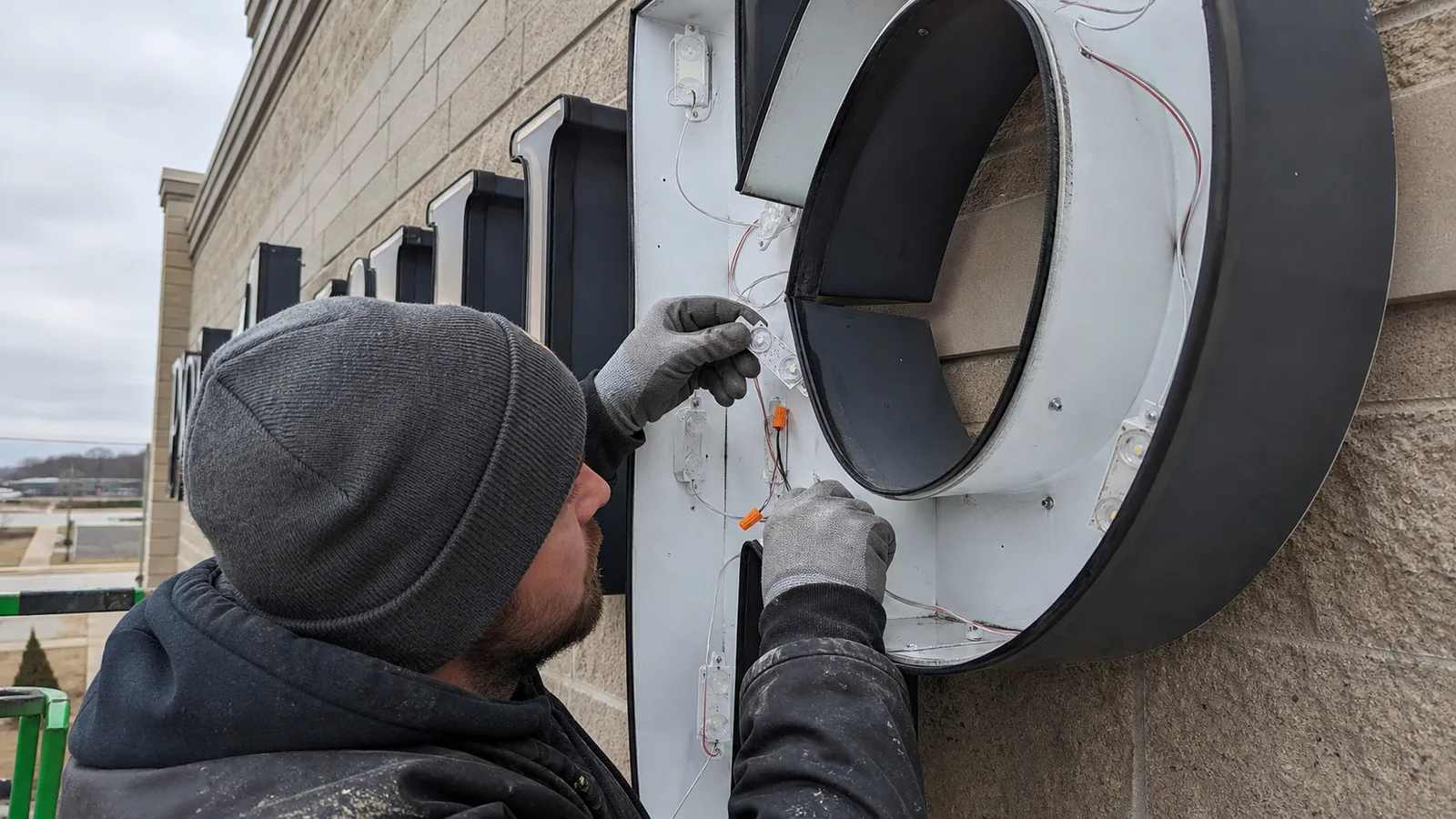 Technician replacing LED modules inside an open commercial channel letter