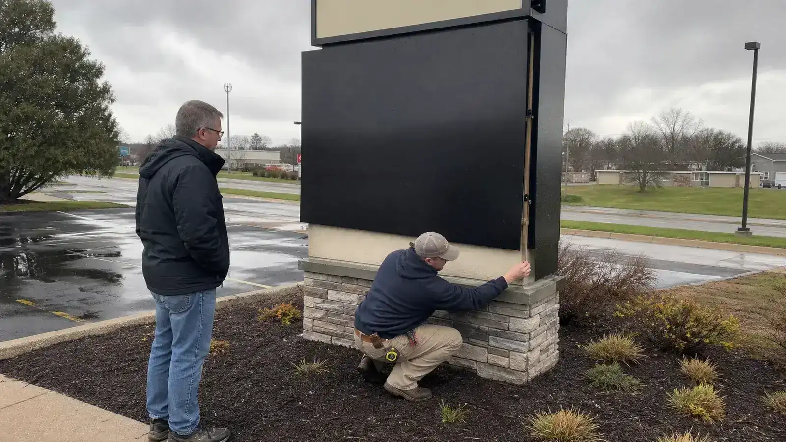 Technician checking a freestanding pylon sign panel after a Midwest storm