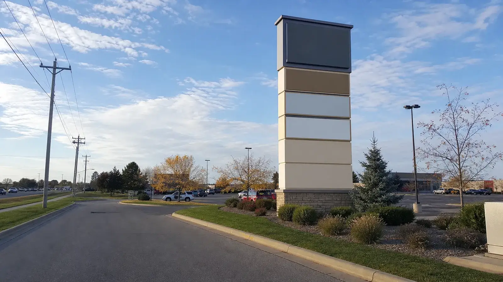 Tall blank-panel pylon sign at a landscaped Wisconsin shopping center